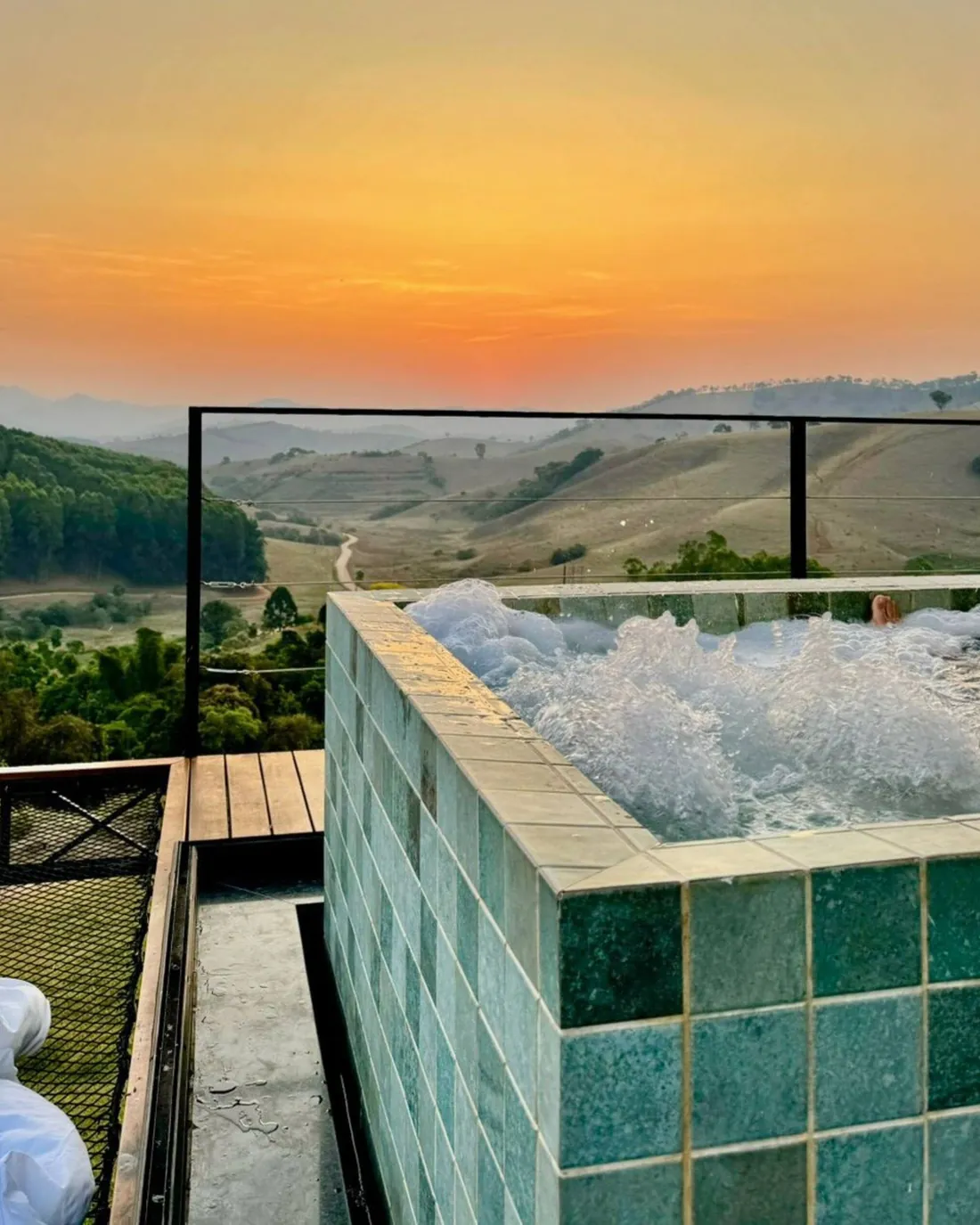 Solarium 1: piscina de borda infinita de azulejo esmeralda com vista para os cafezais e a Serra da Mantiqueira
