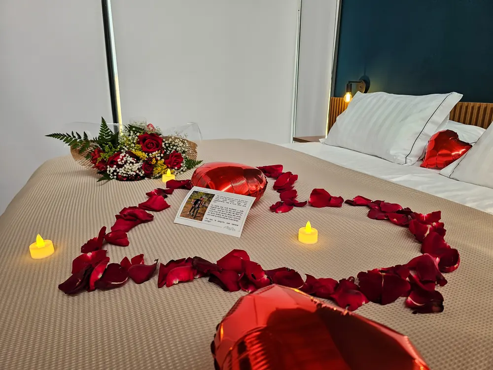 Cama decorada com pétalas em formato de coração e velas para data especial