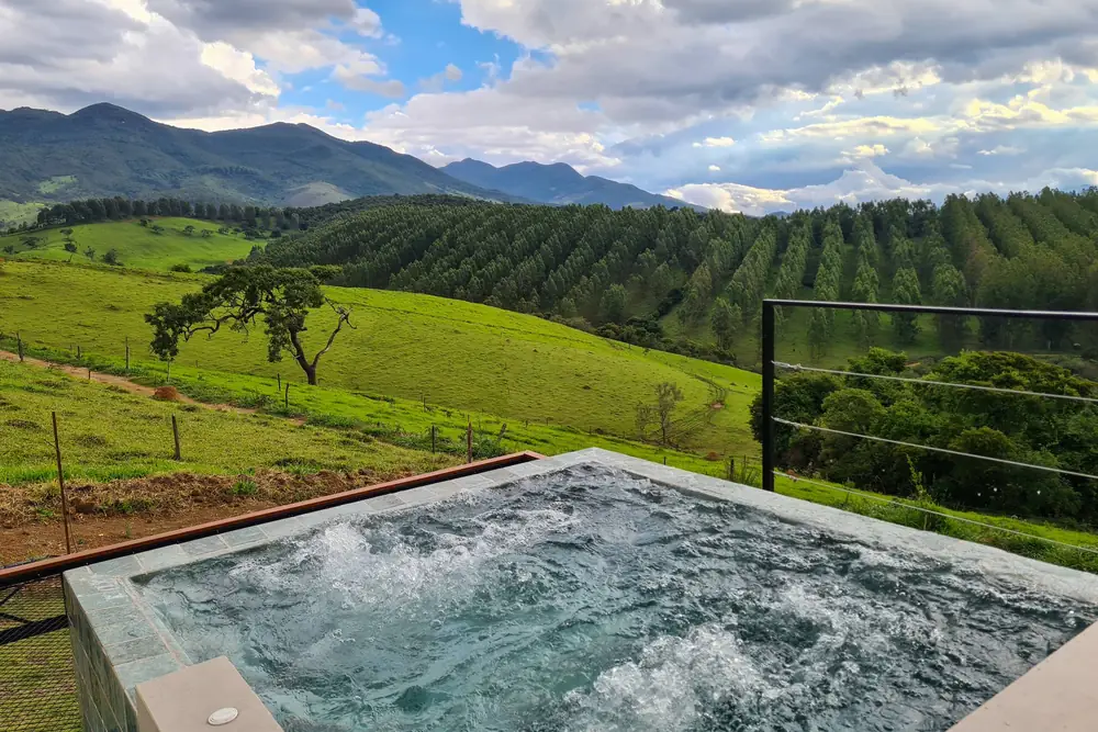 Piscina de borda infinita com os cafezais em terraço ao fundo