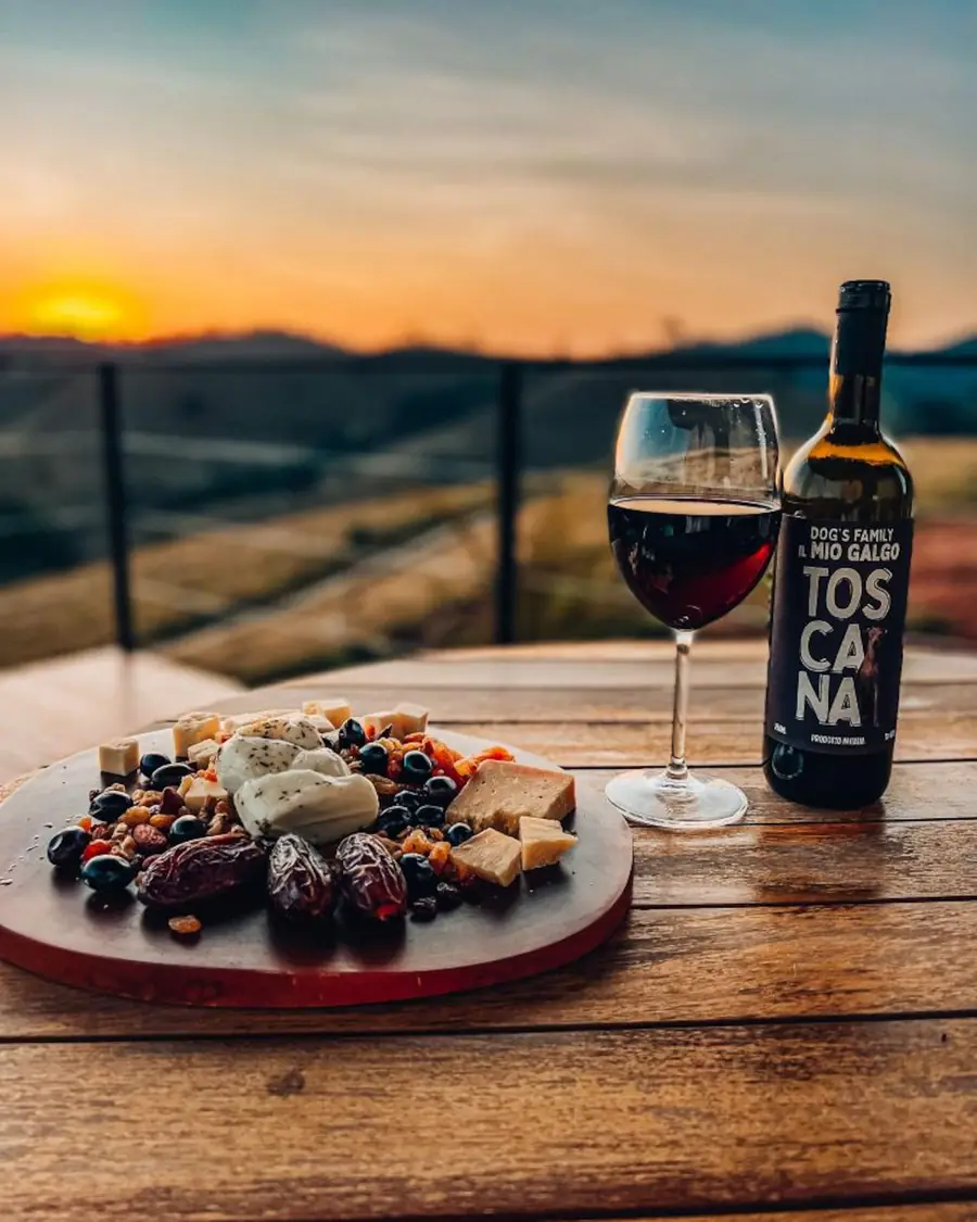 Vinho e tábua de frios no deck durante o pôr do sol